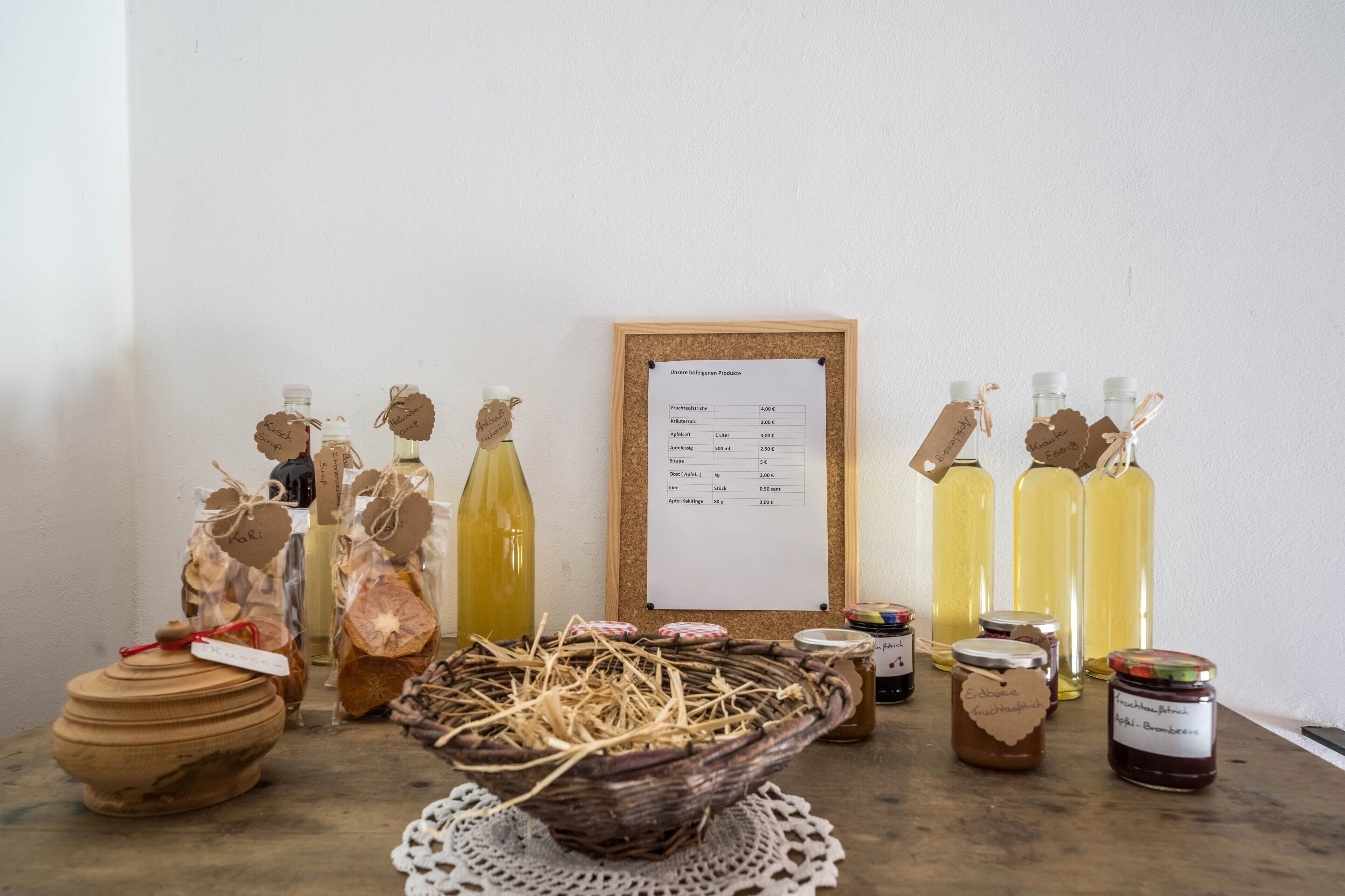 Esposizione di diversi prodotti alimentari, tra cui vasetti e bottiglie, con etichette e un menu su una bacheca.