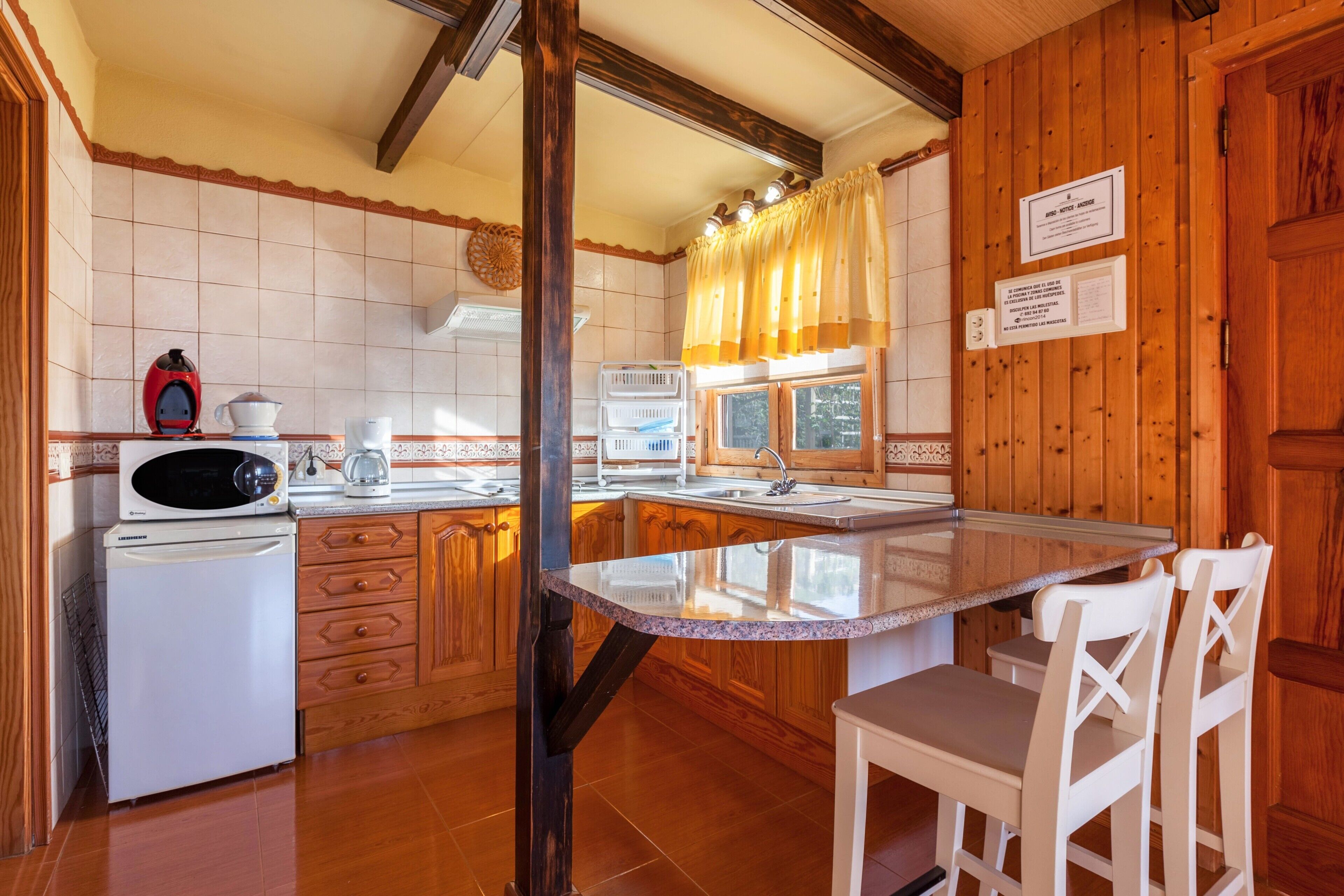 Una cocina con armarios de madera, un refrigerador, un microondas y un lavabo.