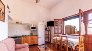 Um espaço compacto com cozinha compacta, área de refeições e sofá.