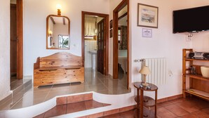 Une chambre avec un lit en bois, un miroir, une télévision et une petite table avec une lampe.