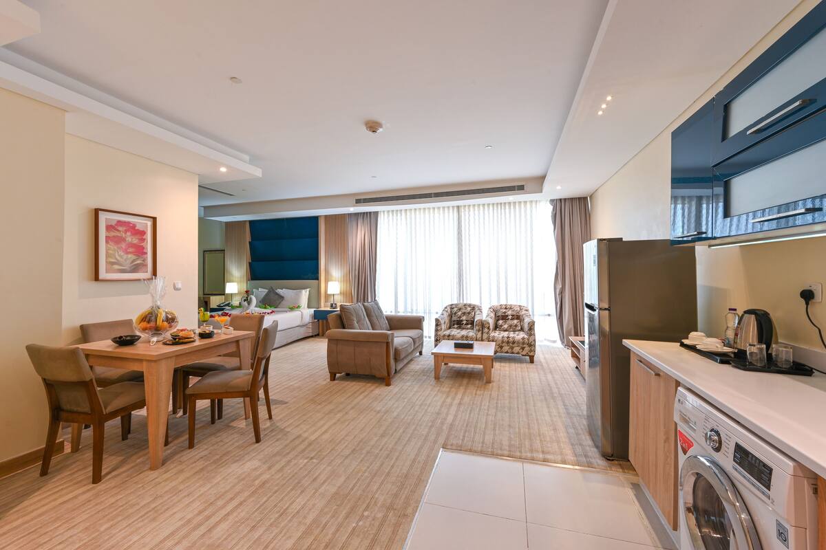 A modern living room with a dining area, a sofa, a coffee table, and a washing machine.