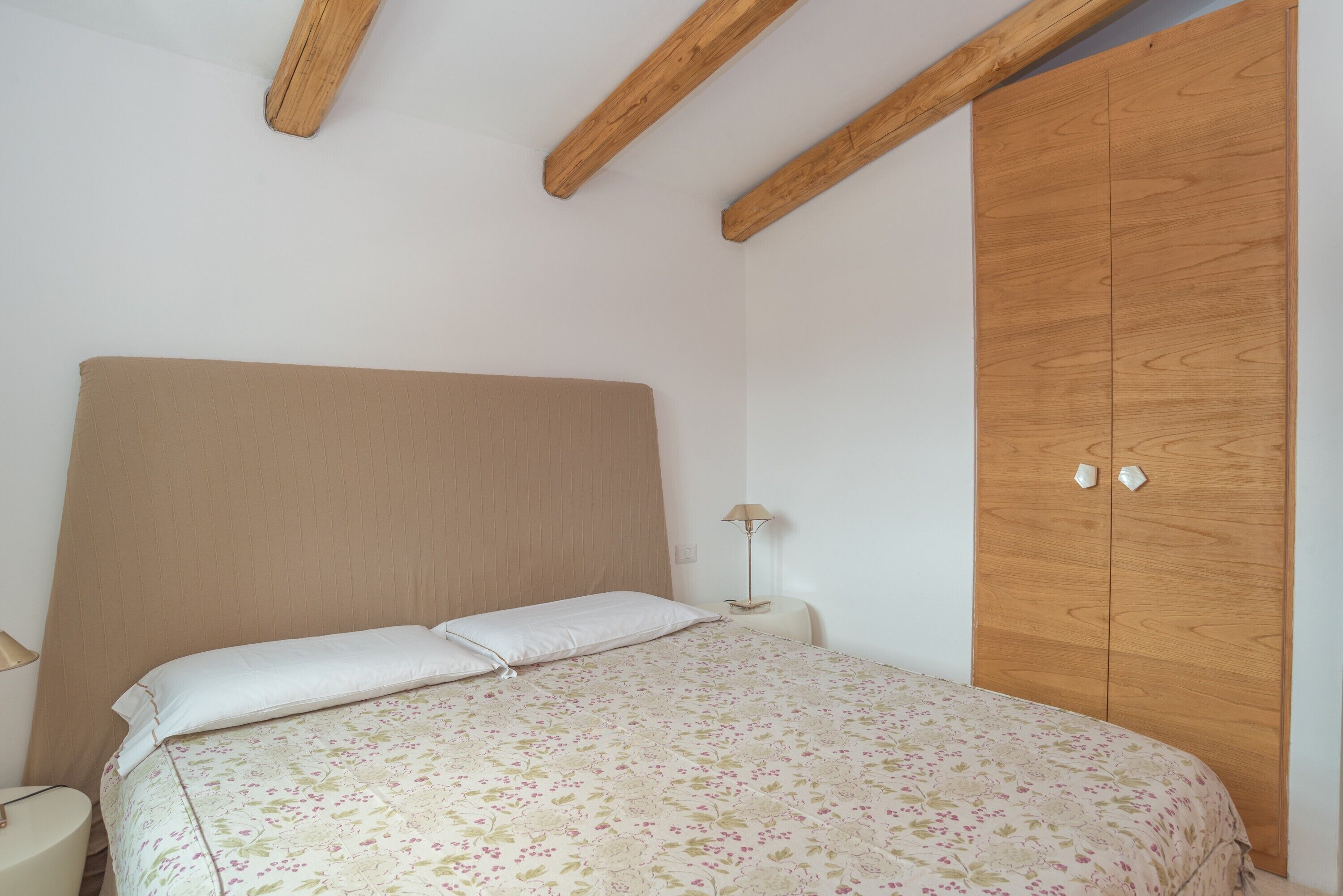Una camera da letto con un letto, un armadio in legno e un comodino con una lampada.