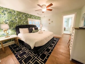 A bedroom with a bed, a nightstand, a ceiling fan, and a patterned wall. - Steps to Dining, Shopping, 3 Minute Walk to Beach (Folly Beach)