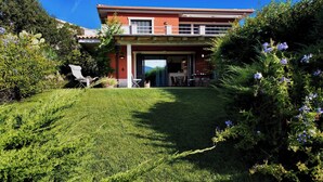 Ein zweistöckiges Haus mit Terrasse, Essbereich und Blick auf die umliegende Landschaft.