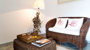 Ein Korpus-Sofa mit weißen Kissen, ein Korpus-Beistelltisch mit Buch und Glas sowie eine Lampe mit weißem Lampenschirm.