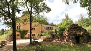 Een landelijk huis met een stenen structuur, omgeven door bomen en groen.