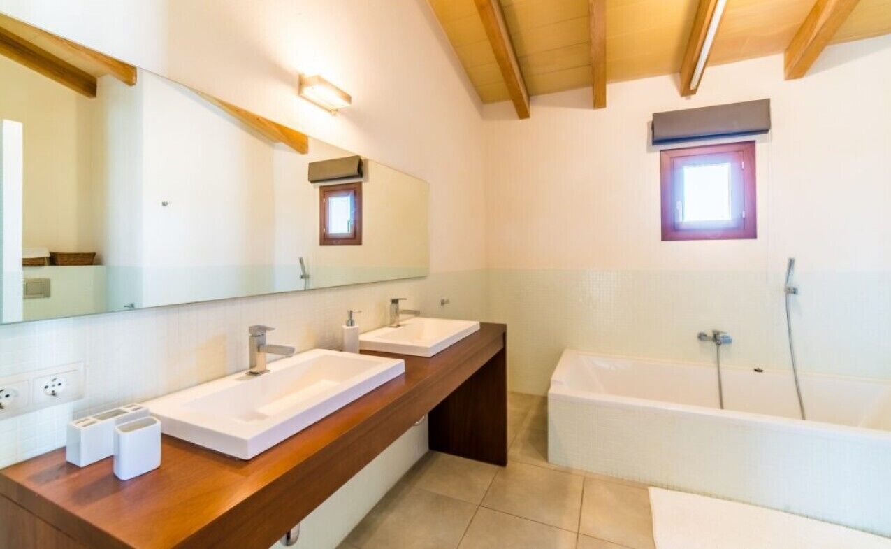 Ein modernes Badezimmer mit zwei Waschbecken, einem großen Spiegel und einer Badewanne.