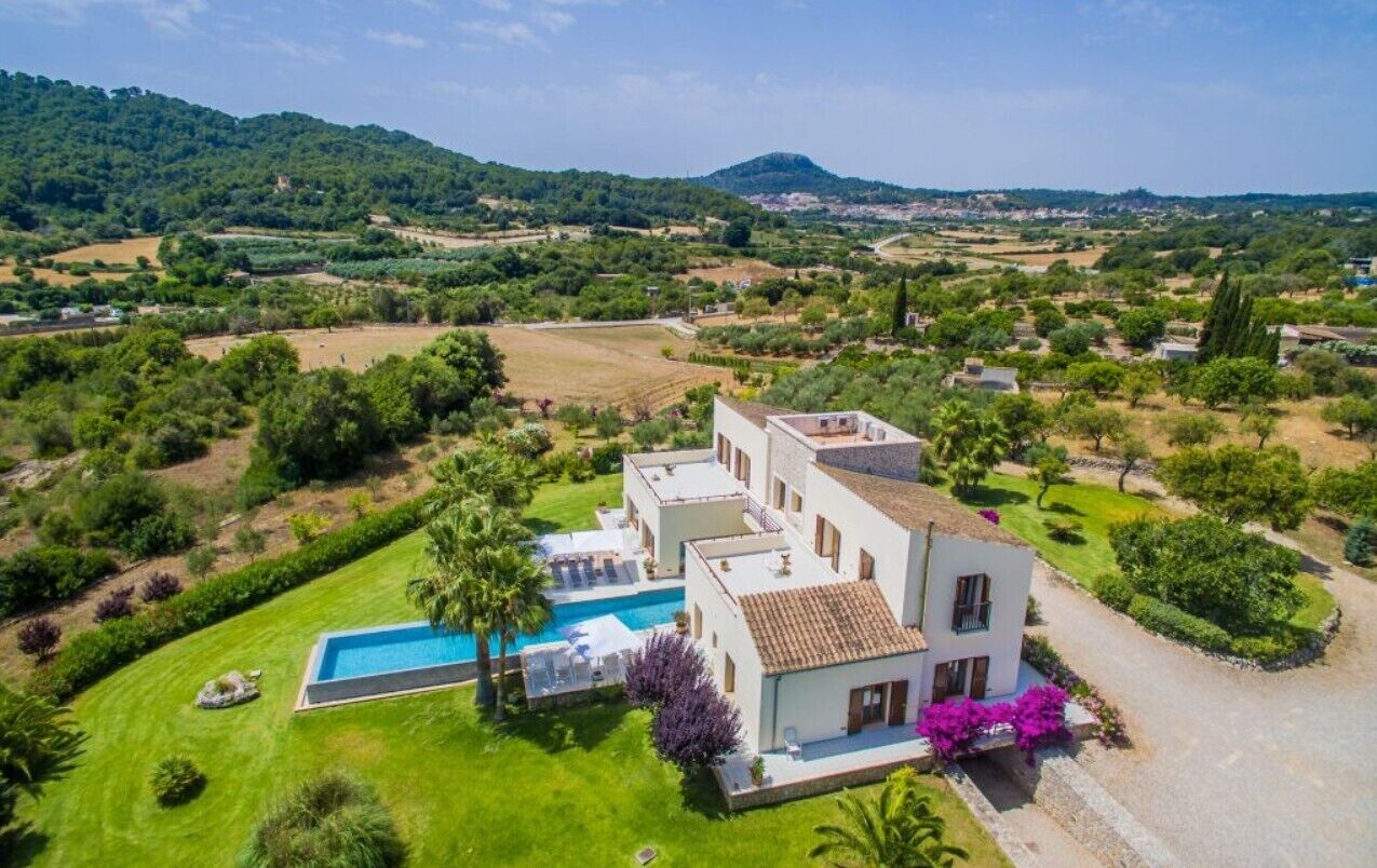 A villa with a swimming pool, surrounded by lush greenery and hills.