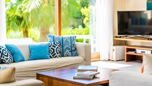 A living room with a sofa, coffee table, and TV. - Villa "Son Sard" with Sea & Mountain View, Pool, A/C, Balcony, Garden & Terrace (Son Servera)