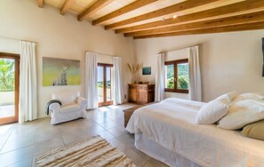 A bedroom with a large bed, a sofa, a wooden cabinet, and a painting on the wall.