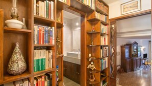 Una biblioteca con estanterías de madera, un jarrón blanco y una lámpara decorativa.