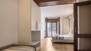 Une chambre à coucher avec un lit, un canapé, un plancher en bois, une porte et une vue sur l’extérieur.