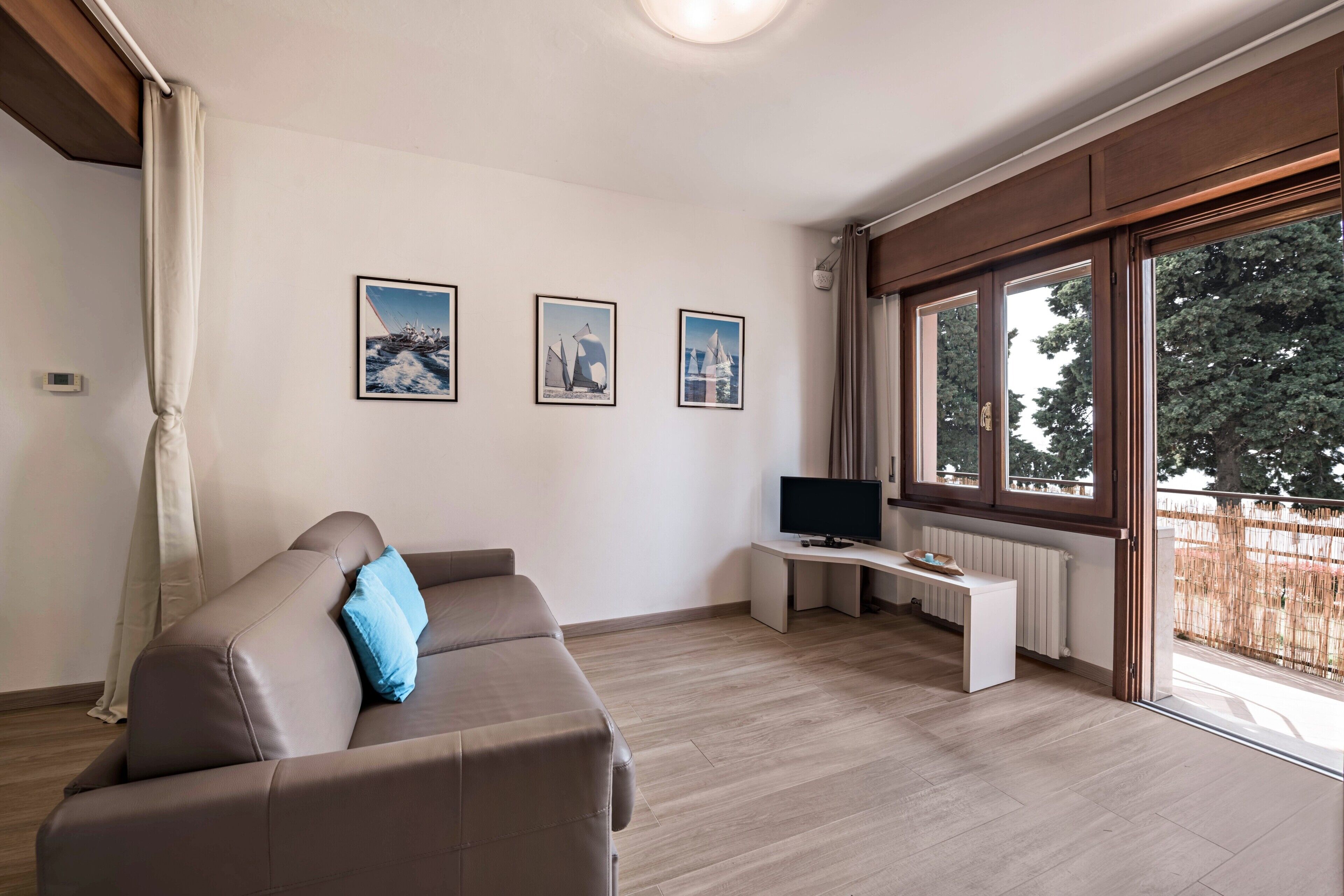 Een moderne woonkamer met een bank, een flatscreen televisie en ingelijste foto’s aan de muur.