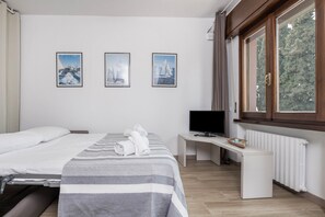 Una camera d'albergo con un letto, una scrivania con la televisione e tre quadri appesi al muro.
