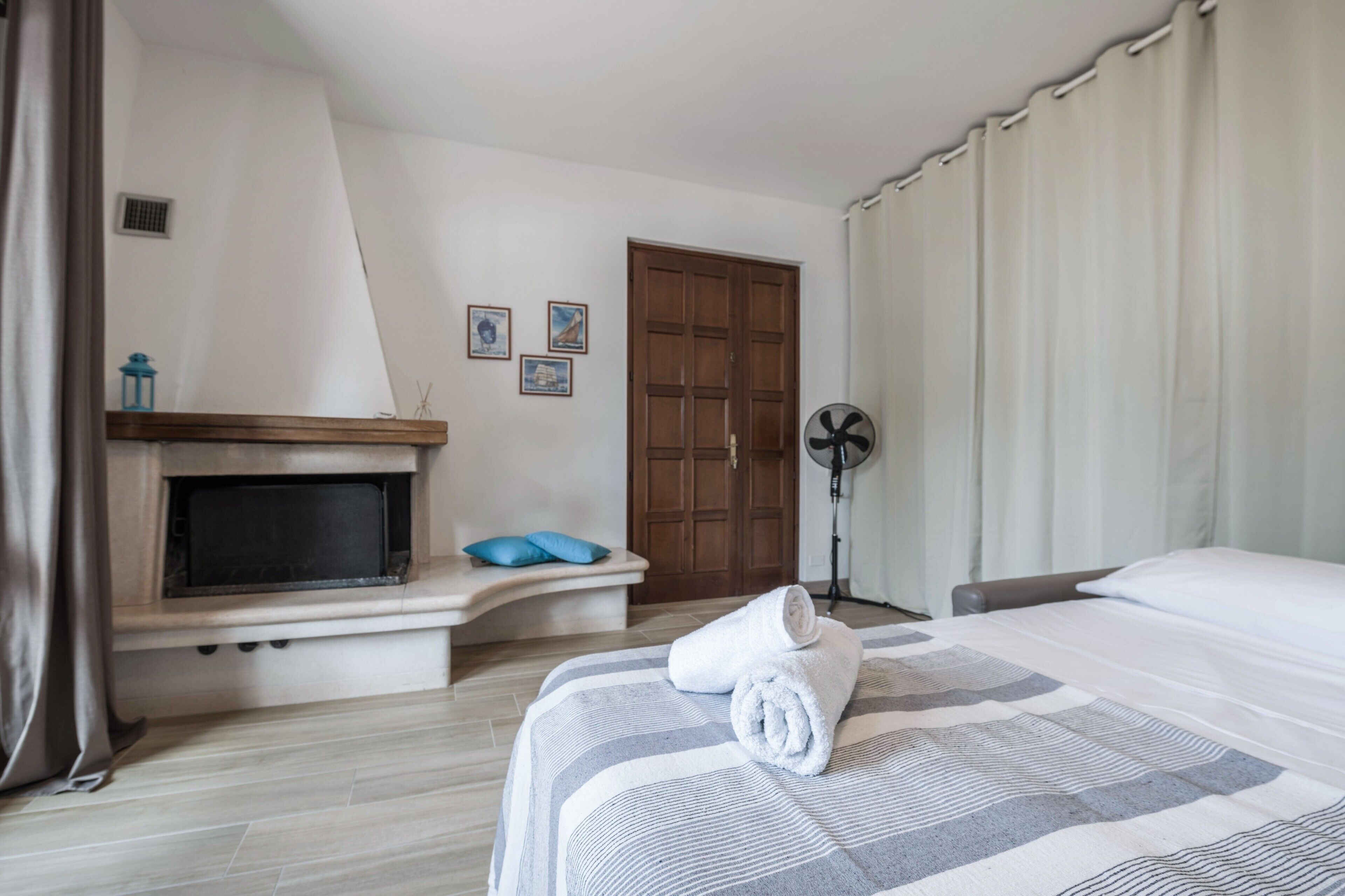 Een hotelkamer met een bed, een televisie, een open haard, een ventilator en een deur.