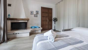 Een hotelkamer met een bed, een televisie, een open haard, een ventilator en een deur.
