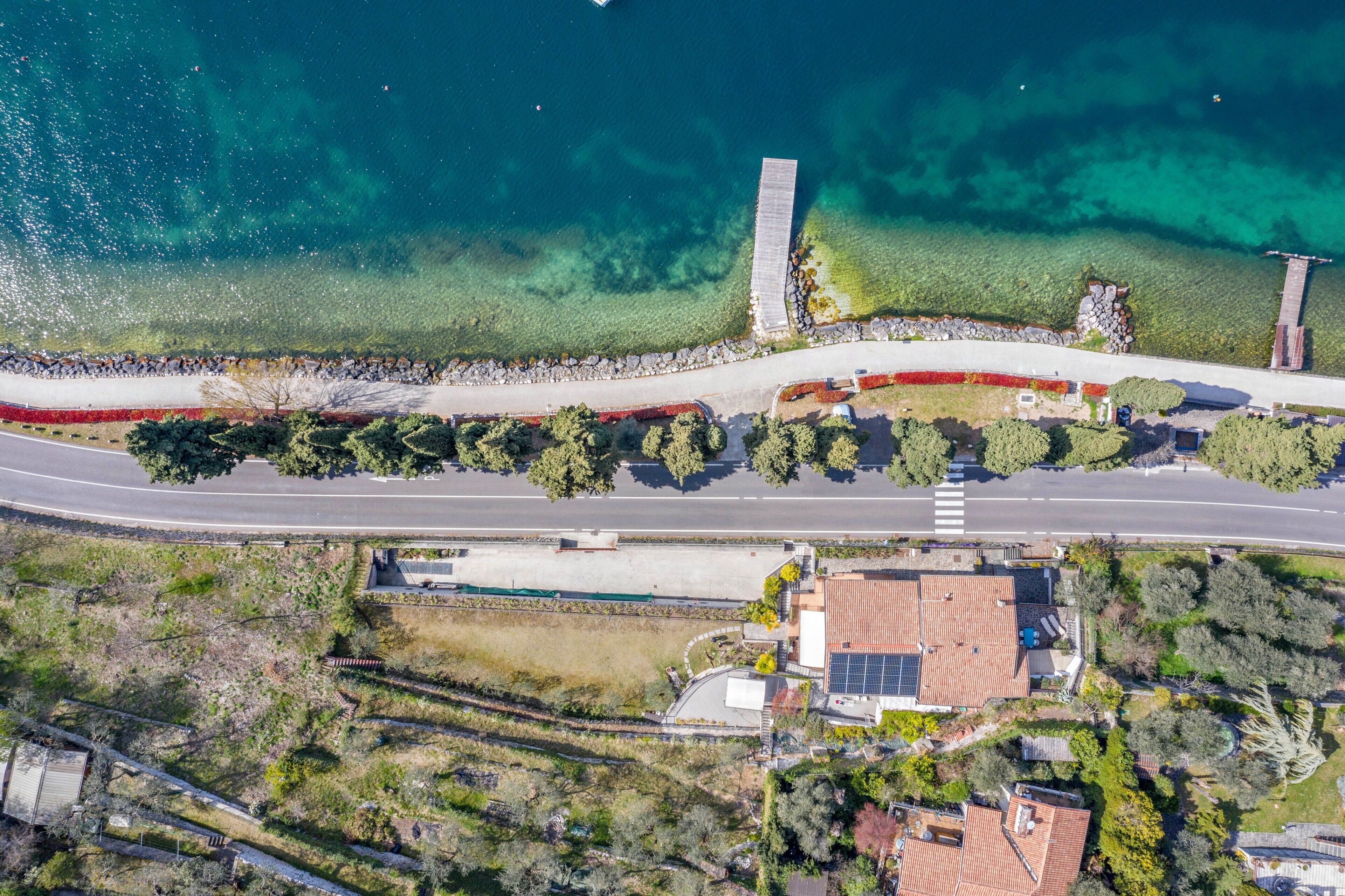 An aerial view of a coastal area with a road, a bridge, and buildings with solar panels.