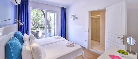 A hotel room with a bed, a desk with a mirror, and a bathroom door.