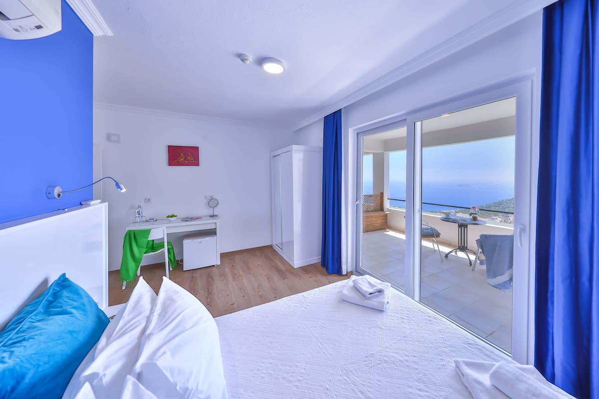 Ein Hotelzimmer mit Bett, Schreibtisch, Stuhl und einem Balkon mit Meerblick.