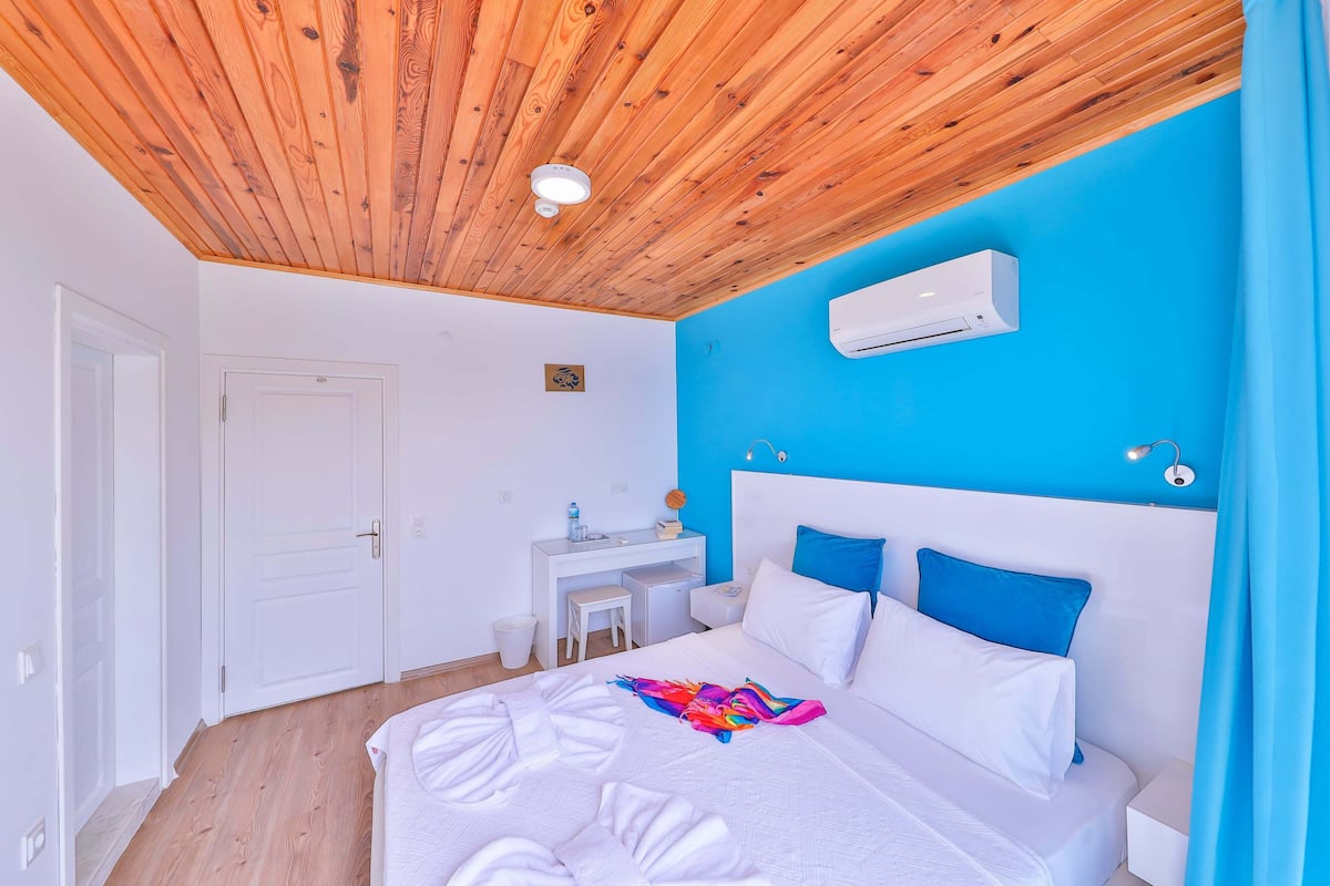 Ein Schlafzimmer mit Holzboden, einem weißen Bett, einer blauen Wand und einer Klimaanlage.