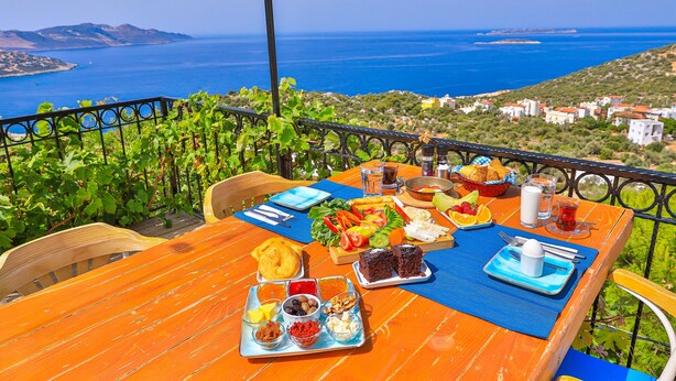 A wooden table set with breakfast items and a view of the sea.