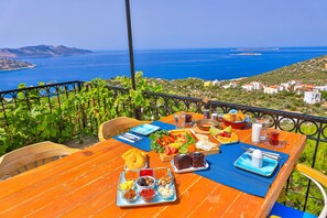 A wooden table set with breakfast items and a view of the sea. - Elit Hotel & Villas Kas (Kas)