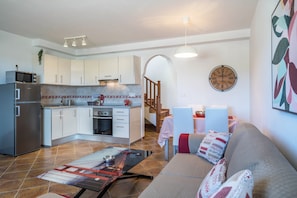 A compact living space with a kitchenette, dining area, and a sofa with patterned cushions.
