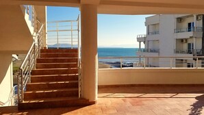 A balcony with a view of the sea, a staircase, and a building with multiple floors. - Hotel La Rosa Negra (Ulcinj)