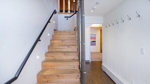 A wooden staircase with metal handrails, leading to a room with a tiled floor and a painting on the wall. - Eiger 9 3 Bedroom Condo by RedAwning (Vail)