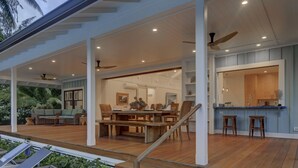 A spacious outdoor deck with a wooden table and chairs, a sofa, and a ceiling fan.