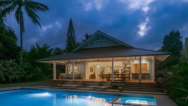 A modern house with a pool, large windows, and a covered patio area.
