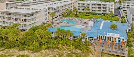 A hotel with multiple floors, a swimming pool, and a beach area with umbrellas.