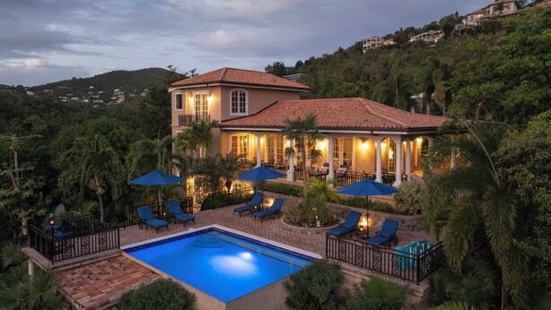 Una casa grande con piscina, mobiliario exterior y vistas de las colinas circundantes.