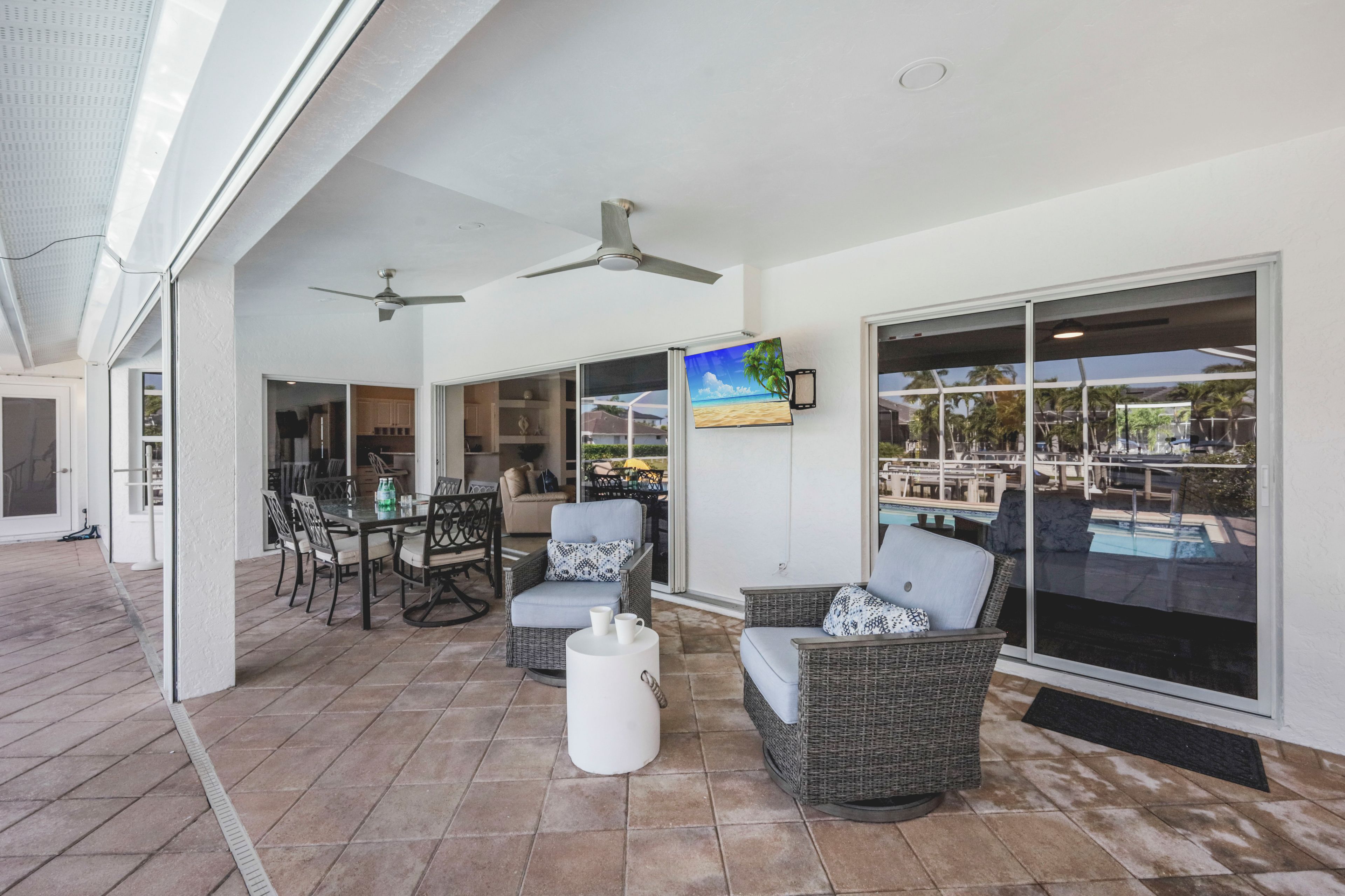 An outdoor patio with wicker furniture, a ceiling fan, and a view of a pool.