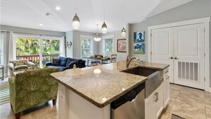 A spacious kitchen with a central island, pendant lighting, and a view to a dining area.