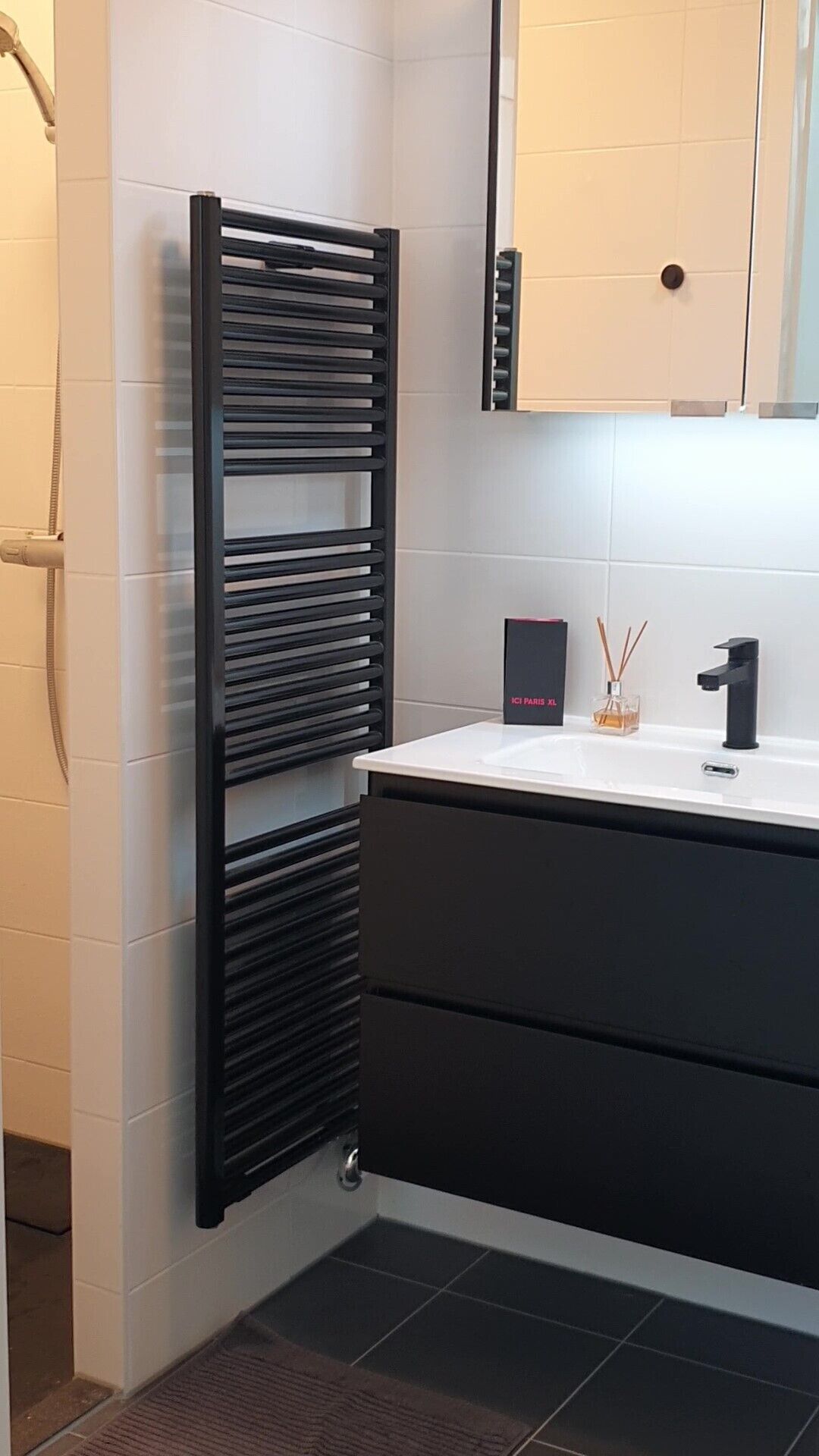 A modern bathroom with a black towel rack, a white sink, and a mirror above it.