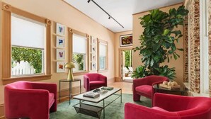 Une pièce avec une moquette verte, des chaises rouges, une table basse et une grande plante.