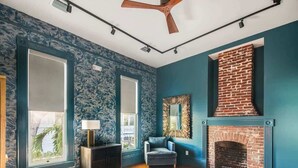 Une pièce dotée d’une grande fenêtre, d’une cheminée et d’un ventilateur de plafond.