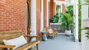 Une façade en briques, un banc en bois et une petite table sur laquelle est posé un vase.