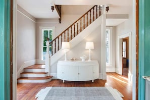 A staircase with wooden balusters, a white console table with lamps, and a patterned rug.