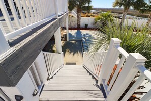 Stairs lead to a deck surrounded by lush greenery and a serene water view.