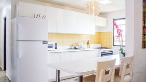 A modern kitchen with white cabinets, a white countertop, a stove, and a microwave. - Casa del Lago Garzas - Suite 101 (Adjuntas)