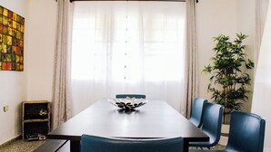 A dining area with a long table, blue chairs, a decorative bowl, and a potted plant. - Casa del Lago Garzas - Suite 101 (Adjuntas)