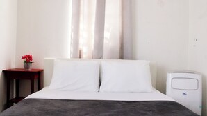 A hotel room with a bed, a bedside table with a flower vase, and a white air purifier. - Casa del Lago Garzas - Suite 101 (Adjuntas)