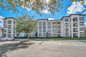 A multi-story residential building with balconies and a parking lot.