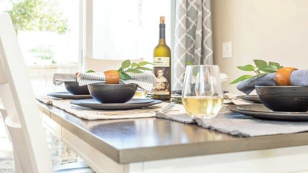 A dining table set with bowls, a wine bottle, and a glass of white wine. - You Had Me at Merlot-Pet Friendly 30 Day (Temecula)