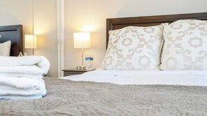 A neatly made bed with patterned pillows, a bedside lamp, and a folded towel on a bedside table. - You Had Me at Merlot-Pet Friendly 30 Day (Temecula)