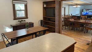 A dining area with a wooden table and chairs, a TV, and a bookshelf.