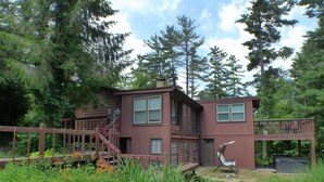 A two-story house with a wooden deck and a staircase leading to the upper level.