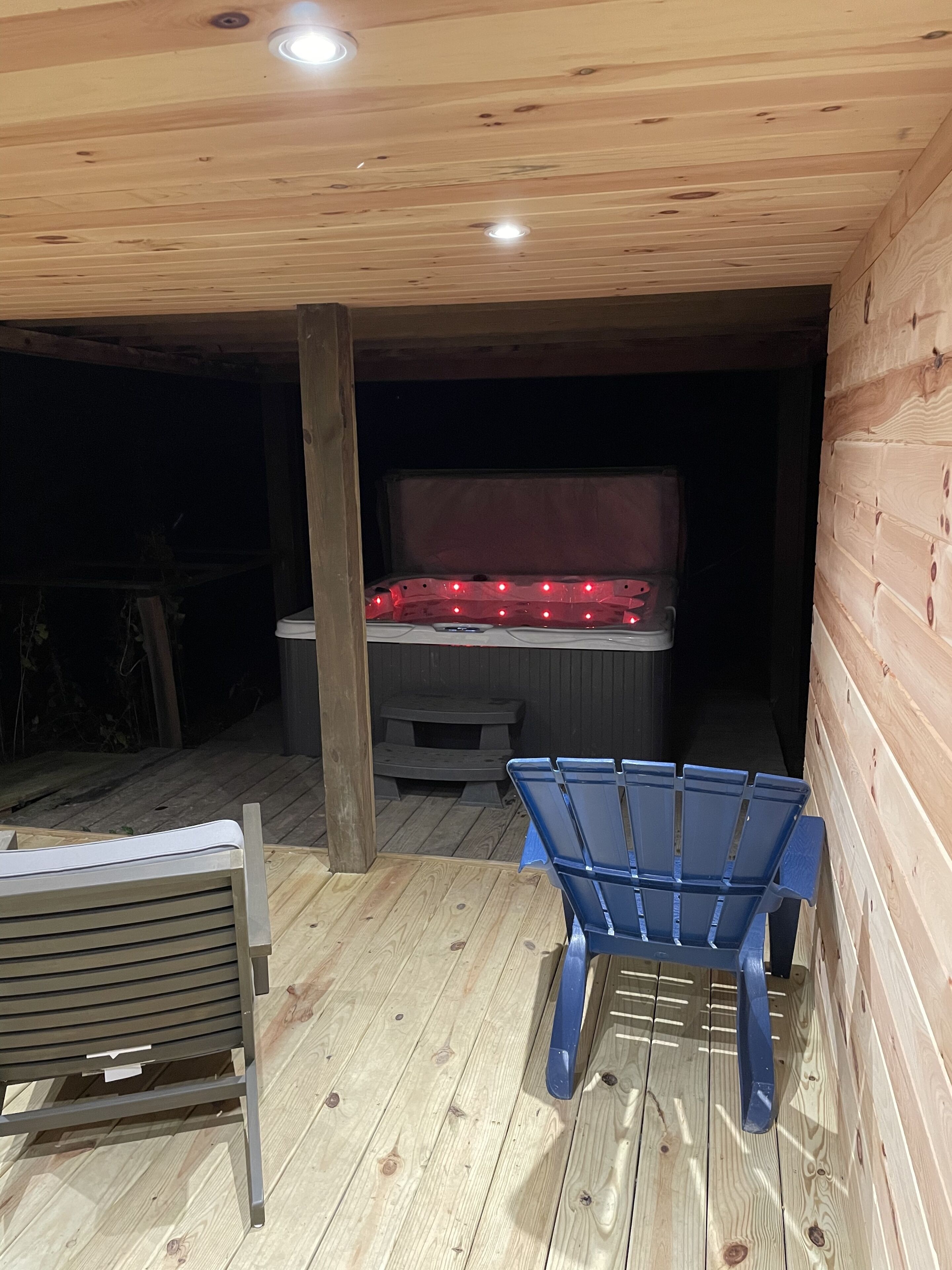 Una terraza de madera al aire libre con dos sillas azules y un banco de madera.
